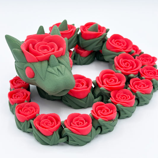 A 3D-printed Cinder Wing Rose Snake Dragon figure by Highly Obtainable, covered in red roses. Measuring 27 inches, the dragon is primarily green and strategically intertwined with intricately detailed roses along its body, enhancing its mythical appearance. The overall aesthetic is a blend of fantasy and floral elements.
